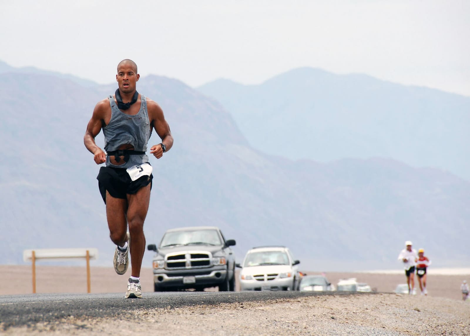 Trkač na pustinjskoj cesti u Dolini smrti tijekom ultramaratona Badwater, s planinama u pozadini