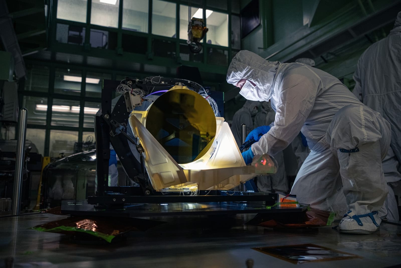 Tehničar u čistoj sobi NASA-e Goddard pregledava prototip teleskopa LISA boje jantara iz 2024. godine